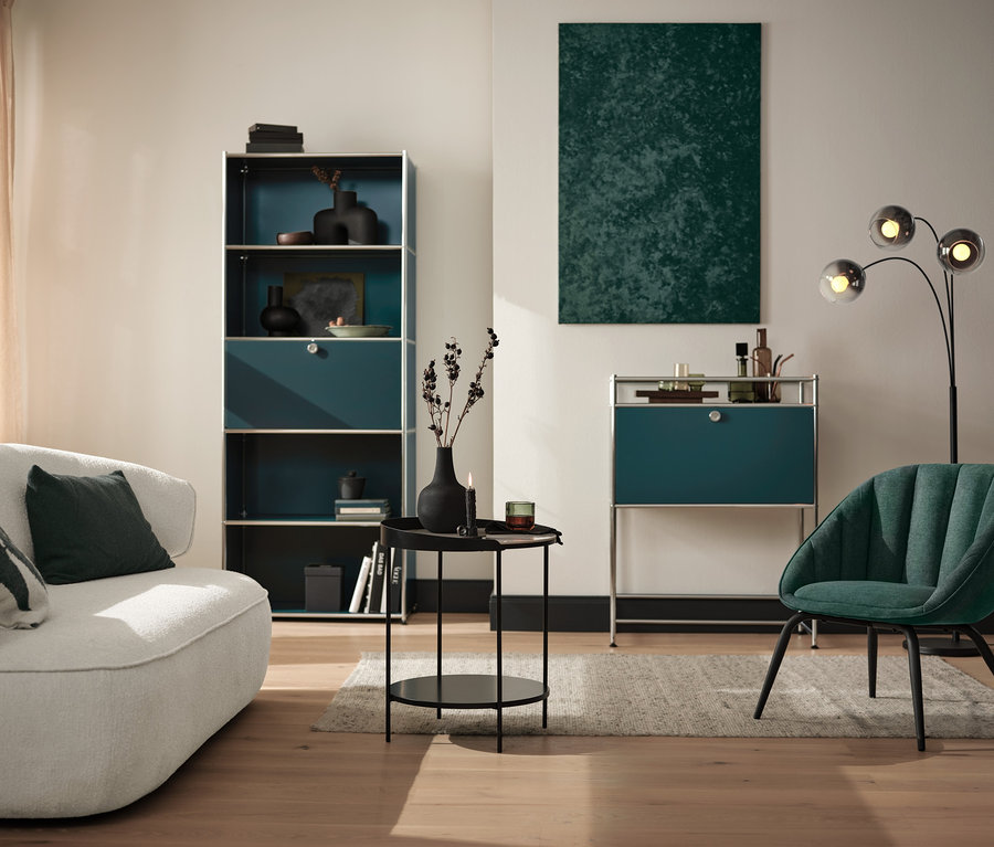 Salon avec étagère haute « CN3 » avec abattant, lampes recourbées, table basse, console « CN3 » et chaise rembourrée.