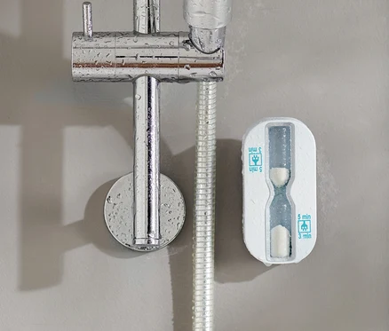 Un sablier de douche fixé au mur à côté d'une pomme de douche.
