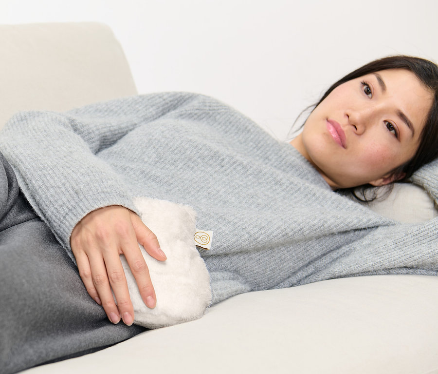 Femme allongée sur un canapé tenant une mini-bouillotte.