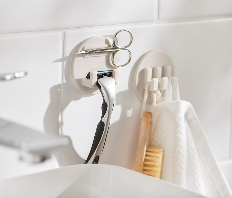 Deux kits de supports auto-adhésifs sur des carreaux blancs, un avec un rasoir et des ciseaux.