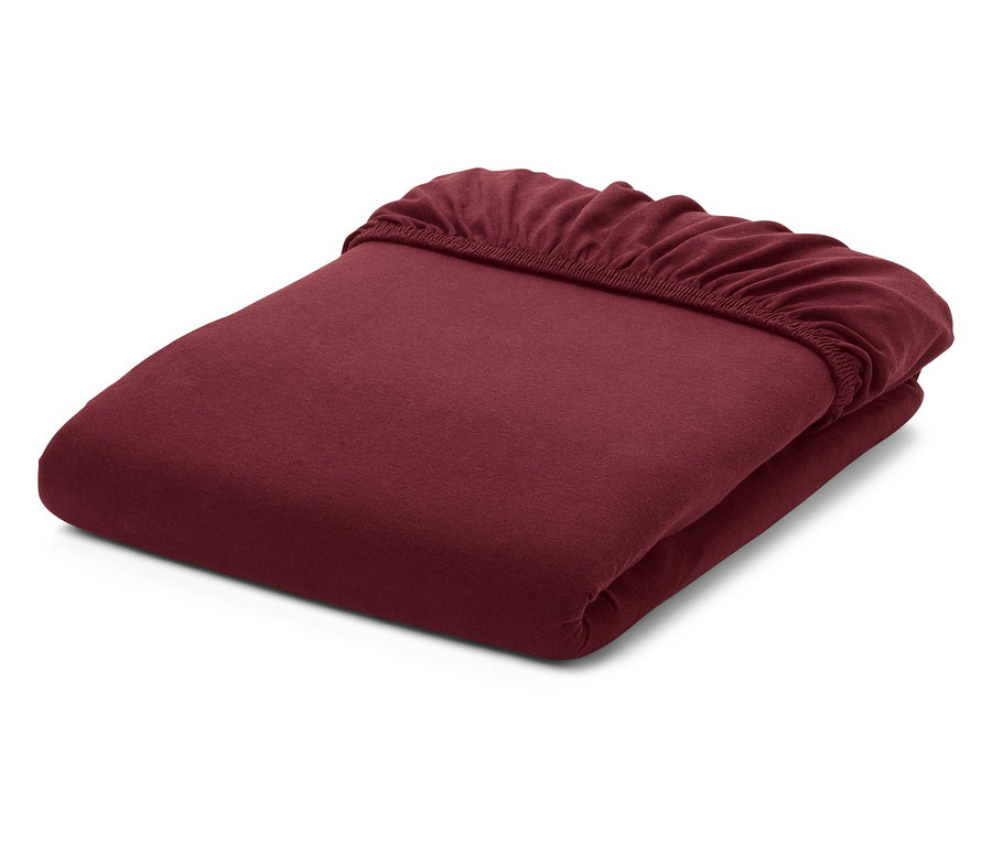 Un drap-housse bordeaux plié sur fond blanc.