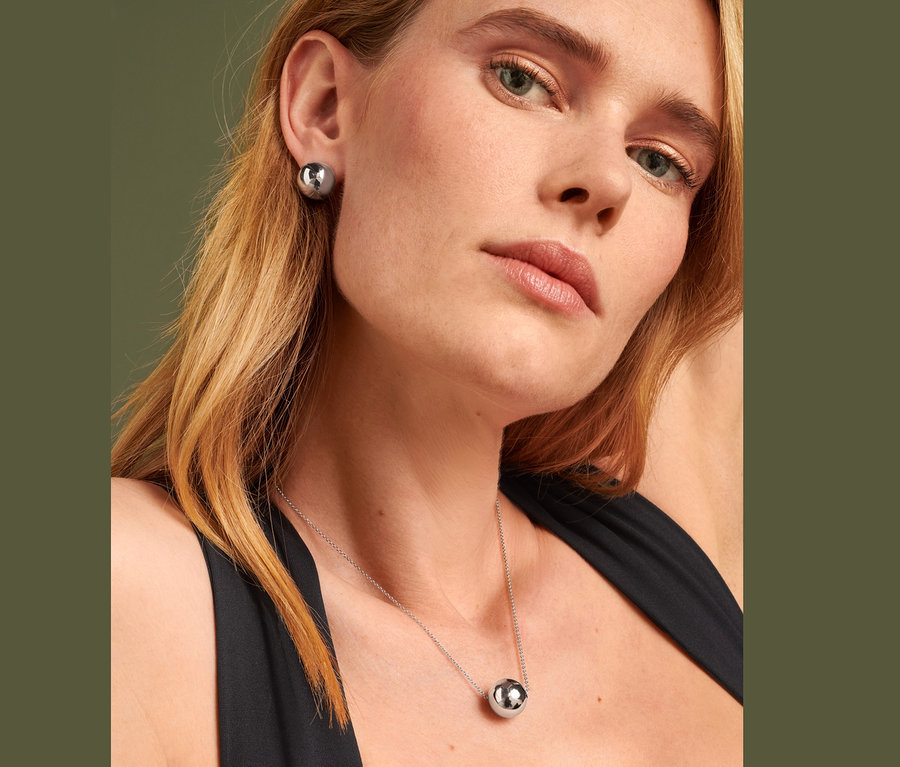 Femme blonde portant des clous d'oreille globe et une chaîne globe.