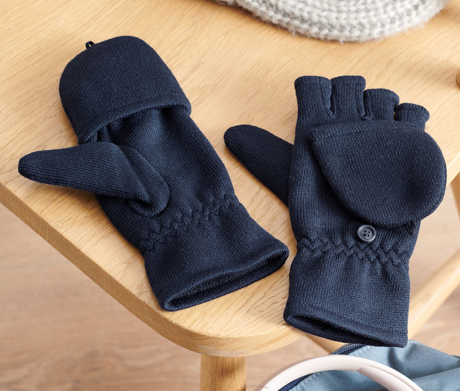 Des moufles et mitaines à rabats en polaire tricotée pour enfant, un bonnet tricoté et un casque audio sont posés sur une chaise en bois sur un sac à dos.