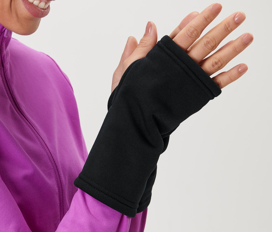 Femme en veste rose enfilant des mitaines noires.