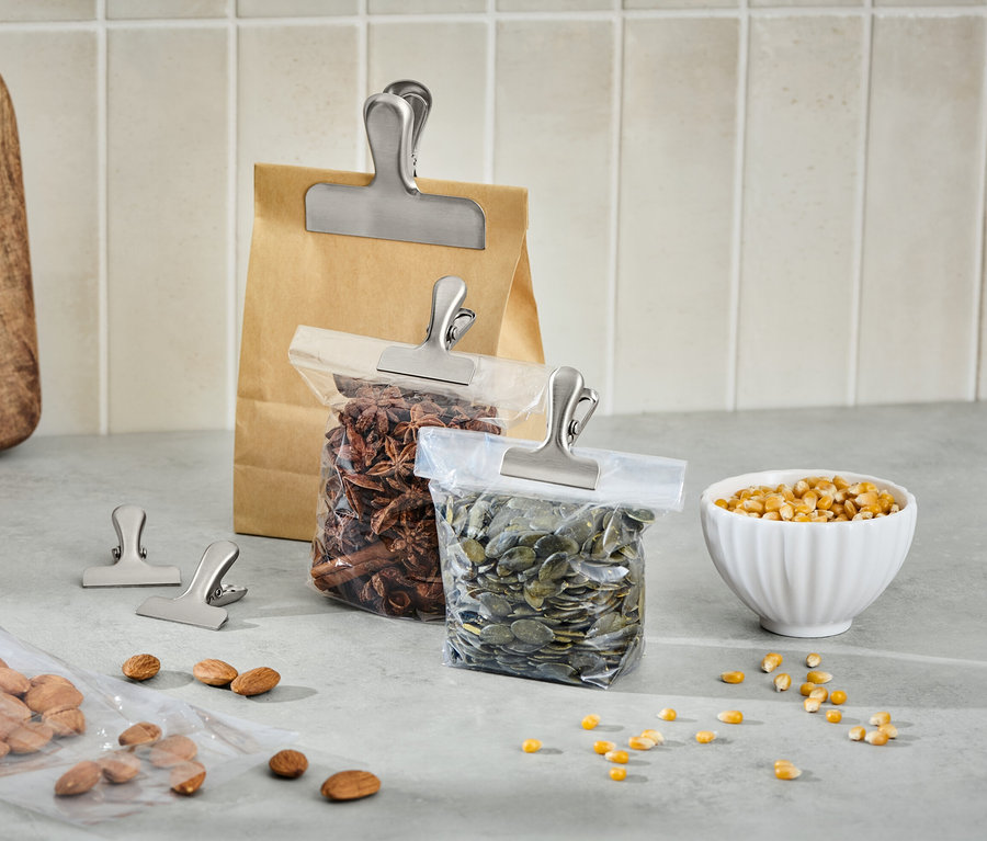 Sur un comptoir de cuisine, des sacs de provisions sont fermés par 5 clips aromatiques en acier inoxydable.