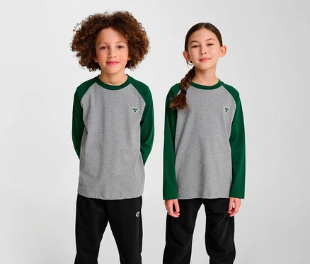 Deux enfants se tiennent côte à côte et portent des t-shirts amples à manches raglan HUMMEL HMLJR BEE verts.