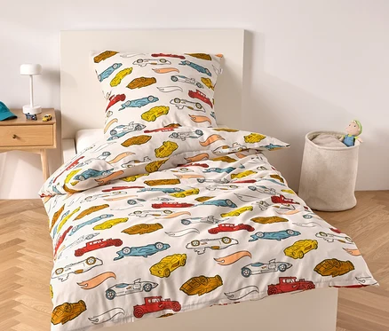 Lit avec cadre blanc et linge de lit à motif de voitures.