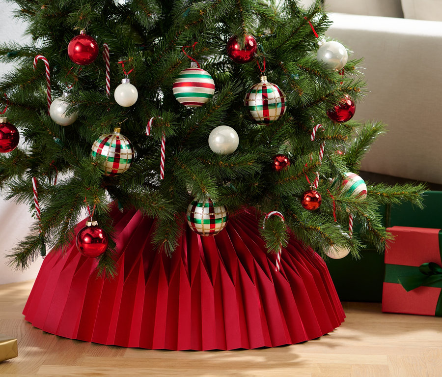 Sapin de Noël décoré de décorations et de bâtons de sucre d'orge, reposant sur une jupe en papier pour sapin de Noël.
