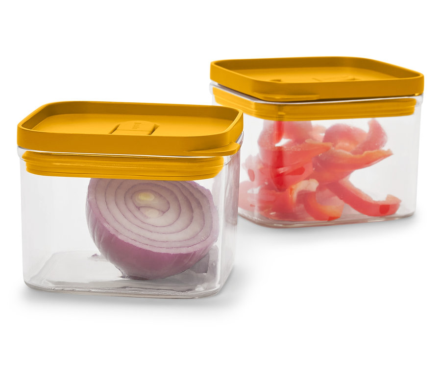 Deux récipients carrés transparents avec des couvercles jaune moutarde. L'un contient un demi oignon rouge, l'autre des poivrons rouges coupés.