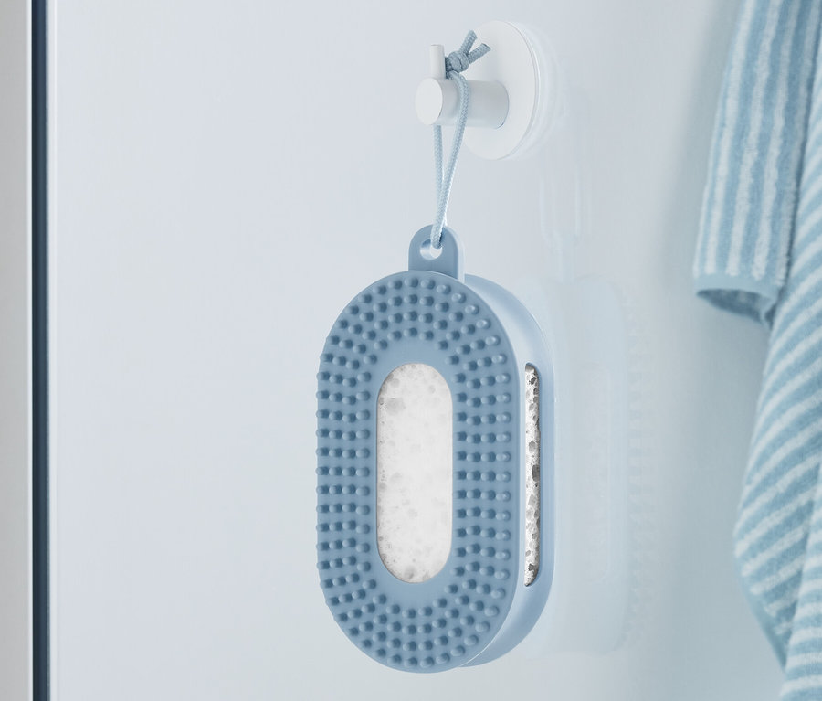 Une éponge de douche bleue est accrochée au mur à côté d'une serviette rayée.