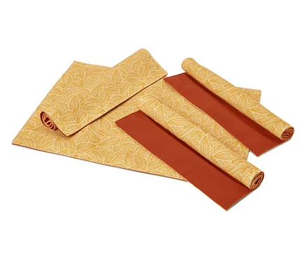 Sets de table à motifs de feuilles dépliés et enroulés et sets de table marron sur fond blanc.