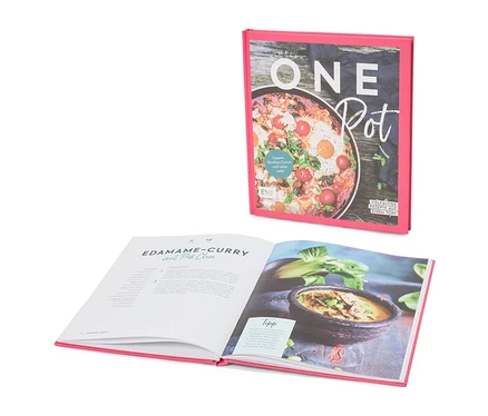 Un livre de cuisine intitulé « Simply One Pot » est ouvert sur une page contenant la recette du curry d'edamame au pak choi.