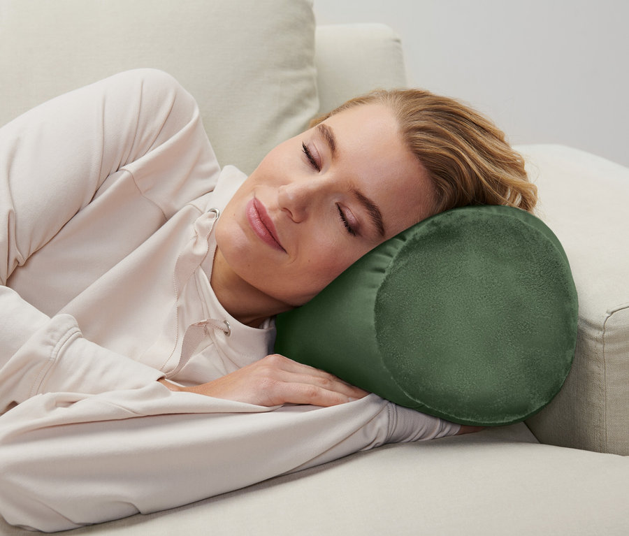 Une femme dort sur un canapé avec un coussin cylindrique sous la tête.