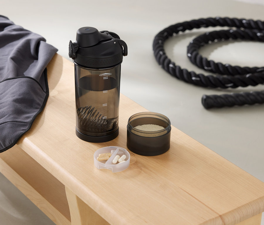 Un sweat-shirt gris, une gourde, une boîte de poudre et une corde sont posés sur un banc.