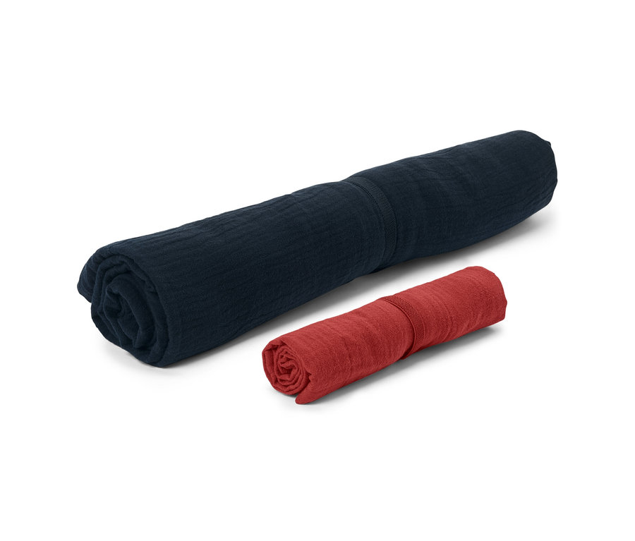 Deux serviettes en mousseline roulées, une bleu marine et une rouge.