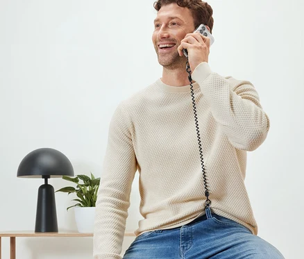 Un homme est assis et téléphone avec une chaîne de sécurité pour téléphone portable.