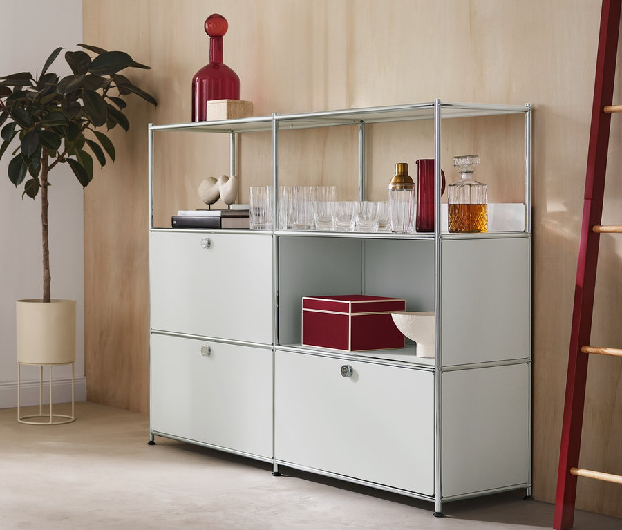 Dans la pièce, il y a un cache-pot rond avec une plante, une commode en métal « CN3 » à 2 abattants et 1 tiroir et une échelle décorative avec des éléments latéraux rouges.