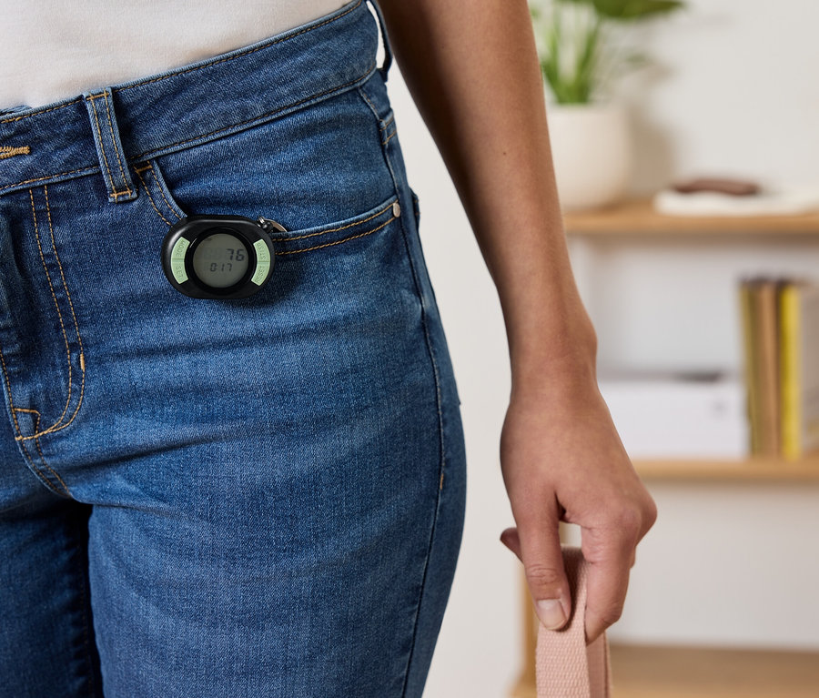 Podomètre noir attaché à la poche avant d'un jean bleu.