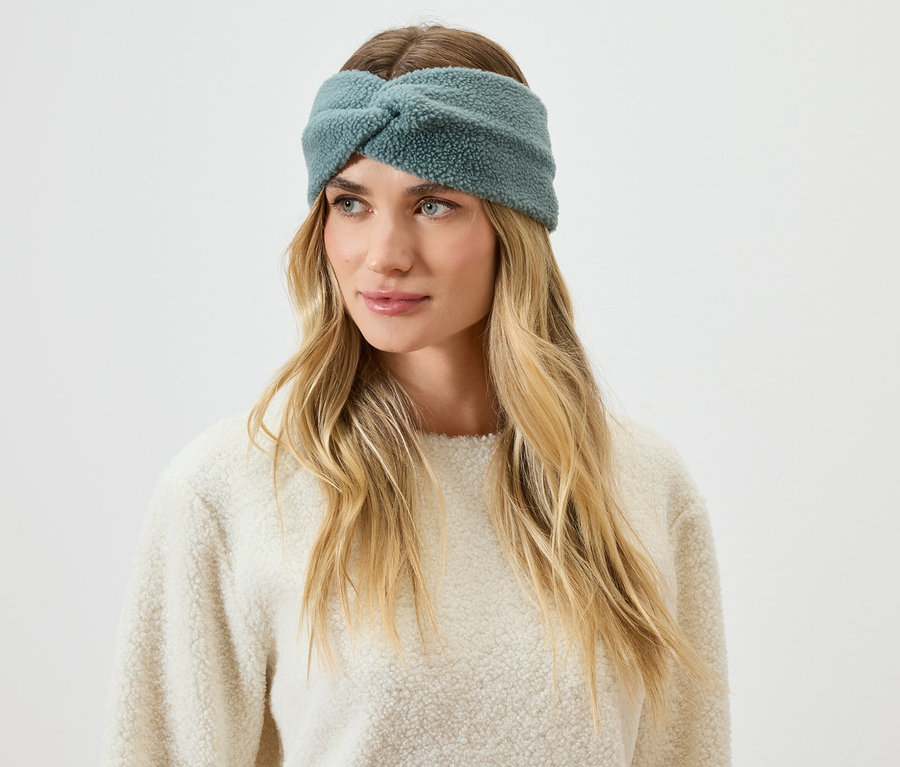 Portrait d'une femme blonde portant un bandeau bleu-vert duveteux.
