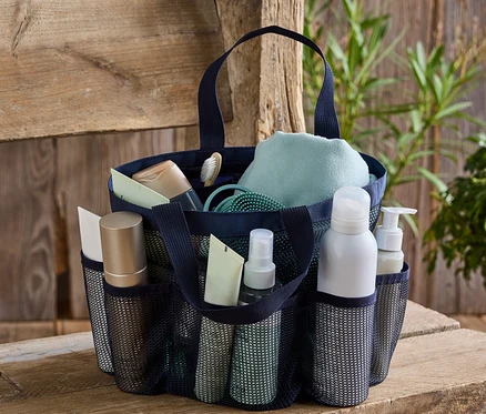 Sac de transport bleu marine avec articles de toilette sur un banc en bois.