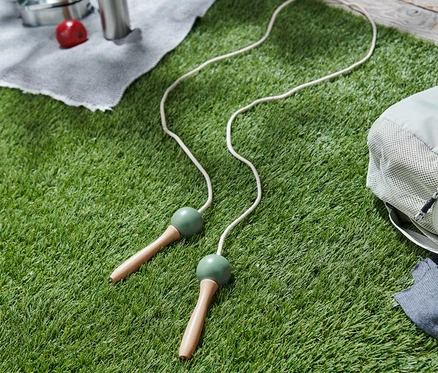 Une corde à sauter blanche repose sur l'herbe à côté d'un sac à dos.