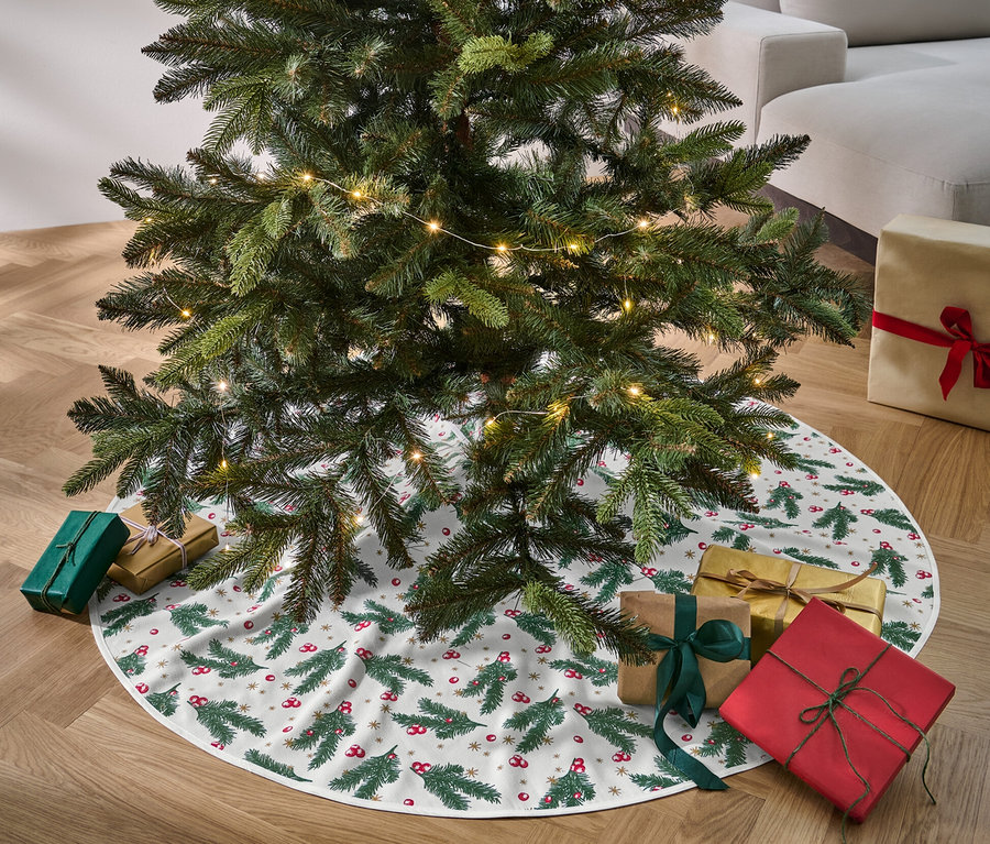 Un sapin de Noël se dresse sur un couvre-pied de sapin, entouré de cadeaux.