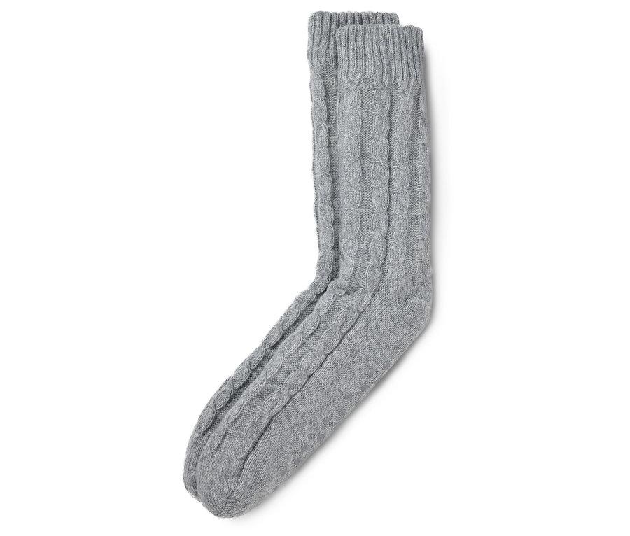 Des chaussettes d'intérieur grises à motif torsadé sont posées sur un fond blanc.