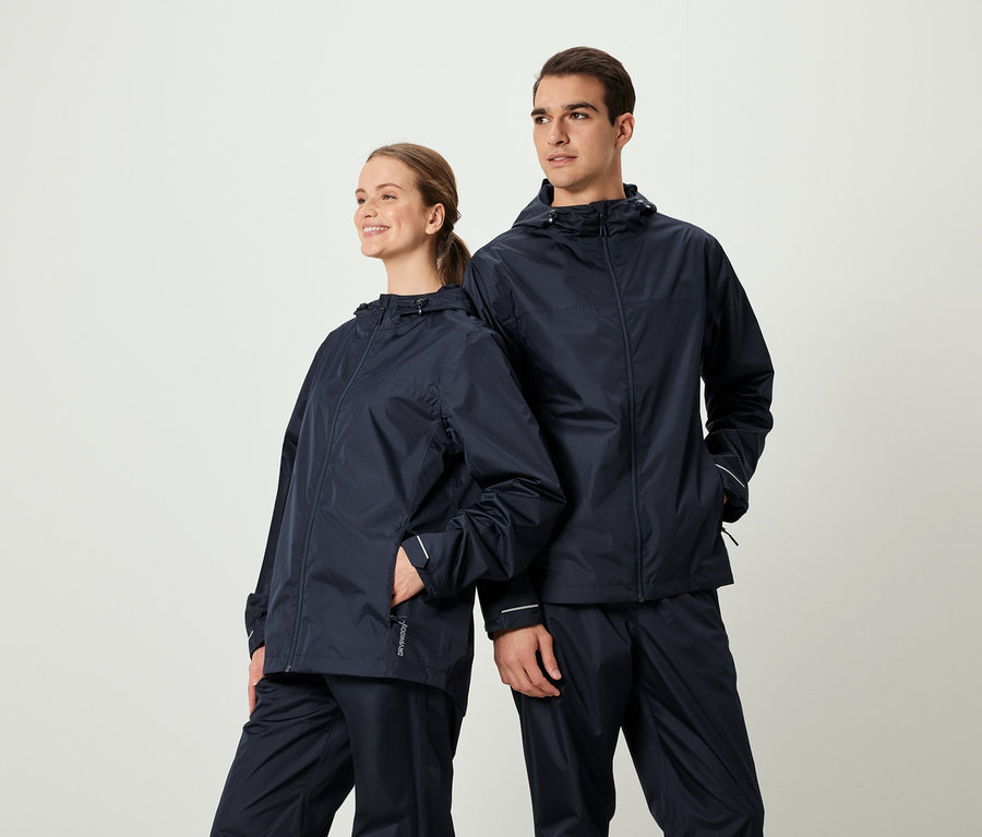 Deux personnes posent vêtues de vestes de pluie et de pantalons bleu marine assortis.