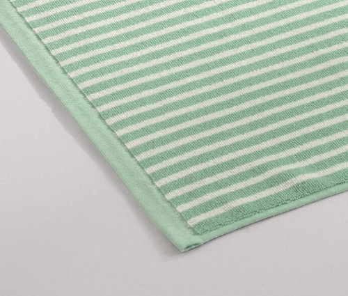 Un tapis de douche vert est posé sur le sol à côté d'une douche.