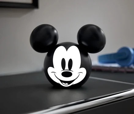 Boule noire avec un visage de Mickey Mouse blanc sur une commode noire.