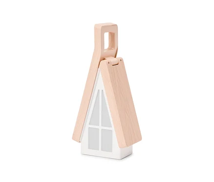 Une lampe blanche en forme de maison avec un toit à pignon en bois clair qui forme une poignée en haut. La façade présente un motif de grille de fenêtre.
