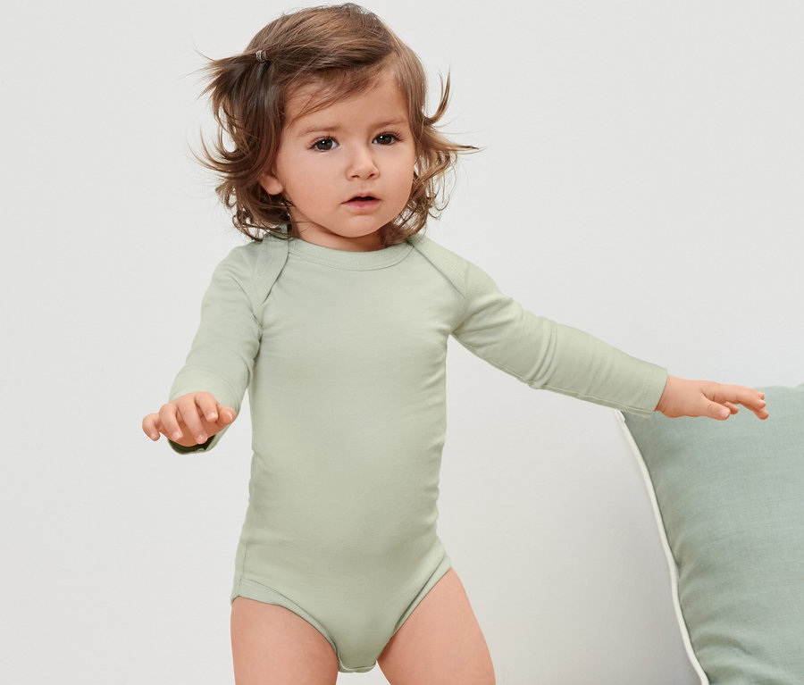 Bambin portant un body vert à manches longues.