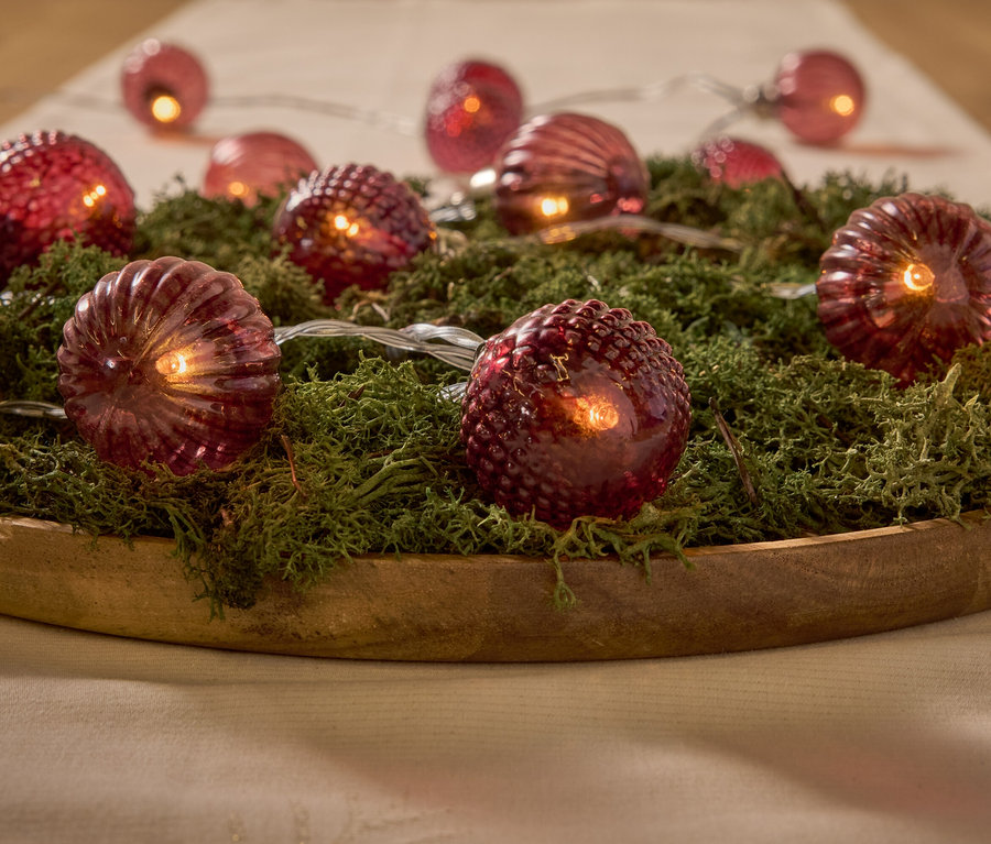 Lumières rouges décoratives sur la mousse dans un bol en bois.