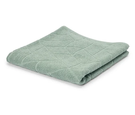 Une serviette vert clair pliée avec un motif géométrique sur un fond blanc.