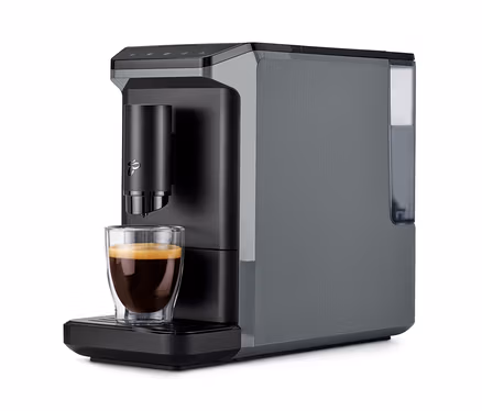 Machine à café entièrement automatique « Esperto mini » grise avec un verre d'espresso sur le plateau égouttoir.