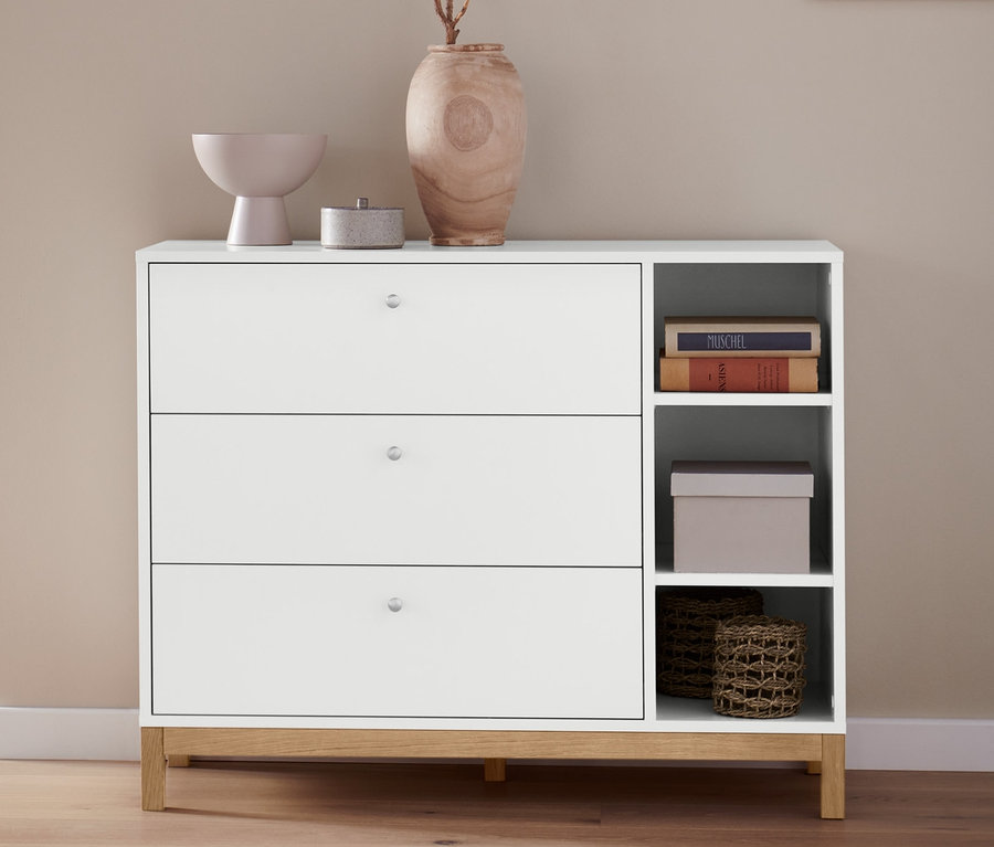 Vue partielle d'une chambre avec un lit à sommier tapissier Scapa gris clair, env. 160 x 200 cm et une commode blanche avec 2 paniers de rangement.