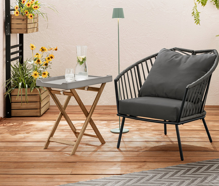 Sur une terrasse en bois se trouvent un fauteuil relax avec revêtement en tissu tressé, un tapis d’extérieur, env. 165 x 115 cm, taupe-gris clair, et un mur végétal « Elin » avec des fleurs. À l'arrière-plan, un lampadaire d’extérieur à LED rechargeable, sauge.