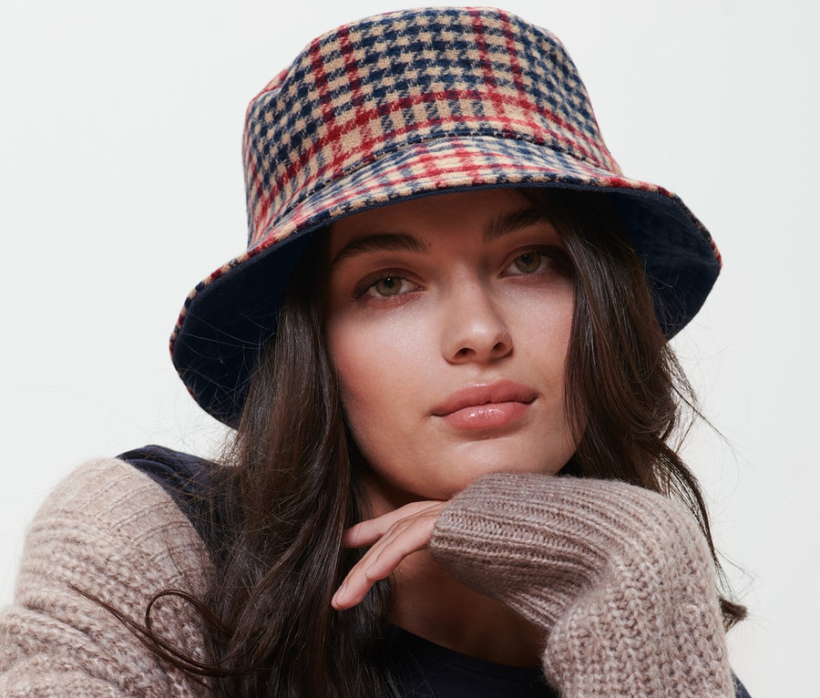 Femme assise sur une chaise et portant un bob réversible.