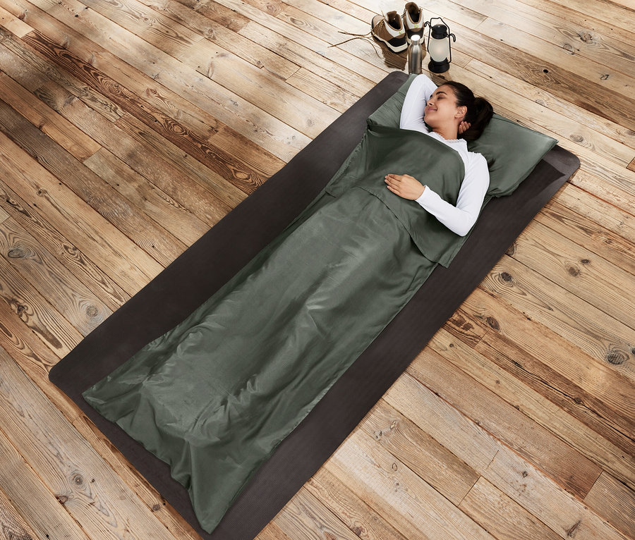 Femme allongée sur un tapis dans un drap de sac de couchage en soie.