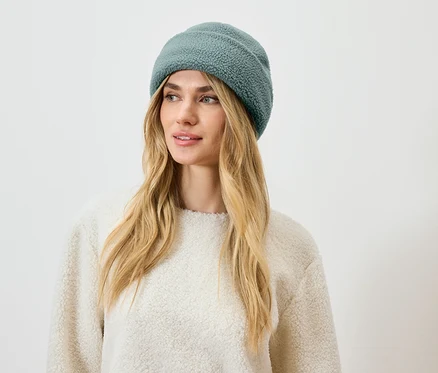 Femme aux cheveux blonds portant un bonnet bleu-vert.