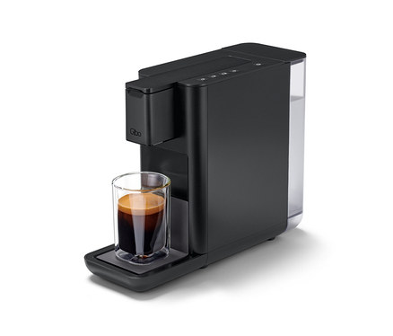 Une machine à café Qbo ICONIC Dark Chrome avec une tasse de café.