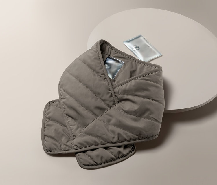 Une écharpe matelassée avec coussin chauffant posée sur une table ronde.