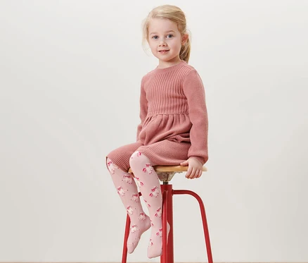 Fille assise sur un tabouret rouge portant une robe rose et 5 collants en coton, rhinocéros.
