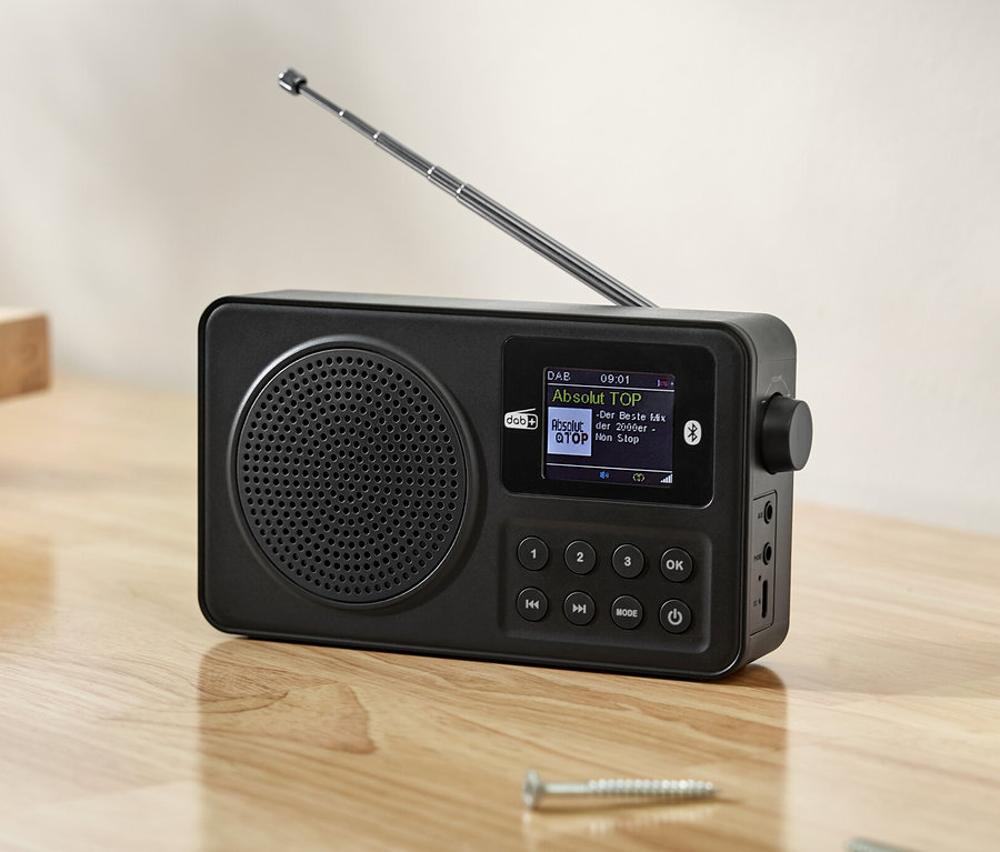 Radio DAB+/ FM noire sur une table en bois avec des outils.