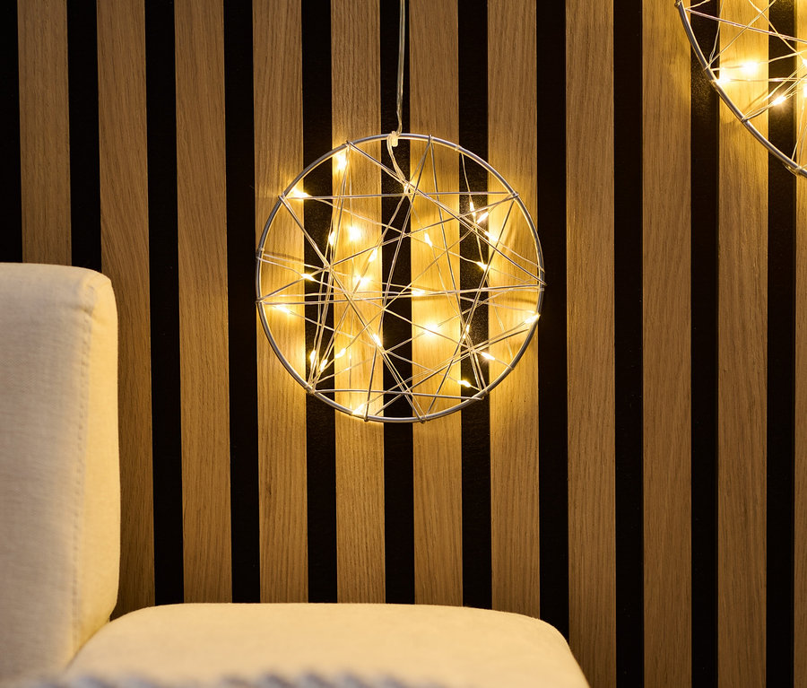 Deux petits anneaux LED suspendus à un mur en bois au-dessus d'un canapé.
