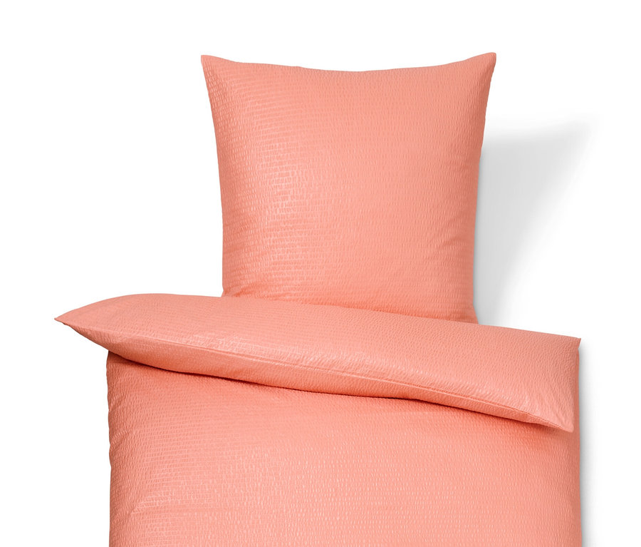 Parure de lit corail en seersucker de taille standard et grande taille sur fond blanc.