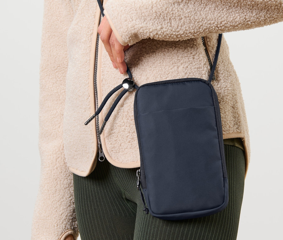 Une femme porte une pochette antigel bleu foncé pour téléphone portable en bandoulière.