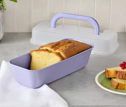 Pain dans un moule rectangulaire violet avec couvercle et deux tranches de pain dans une assiette.