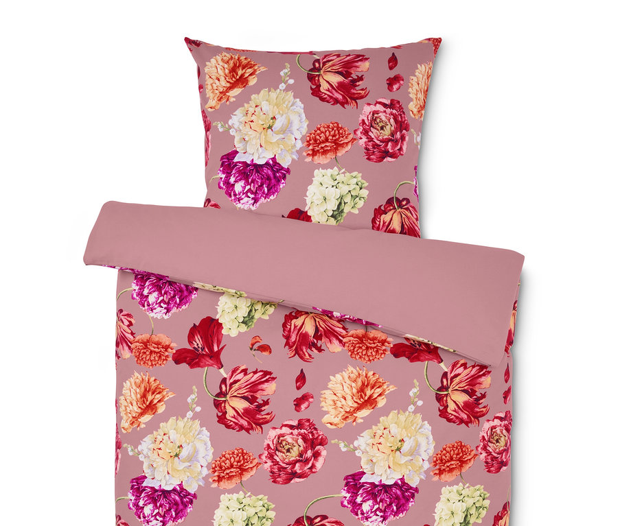 Linge de lit et oreiller avec motif floral sur fond rose.