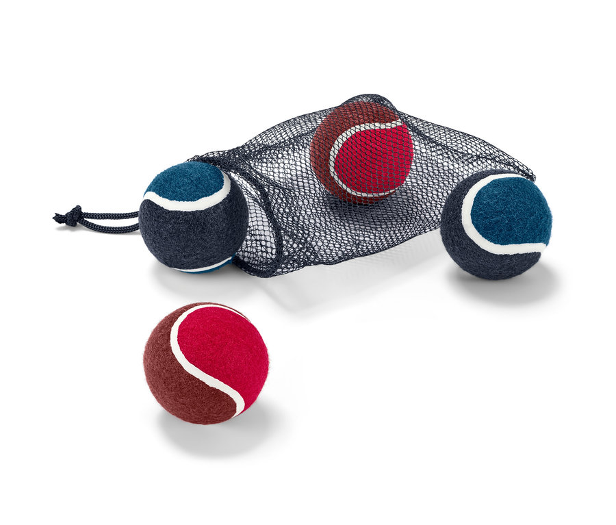 Quatre balles pour chien partiellement dans un sac en filet noir.